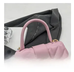 Detalle de bolso rosa acolchado con herrajes dorados y asa redonda de estilo elegante