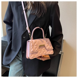 Primer plano del bolso bandolera acolchado rosa con herrajes dorados sobre chaqueta negra