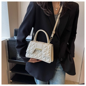 Detalle de bolso bandolera acolchado con hebilla dorada sobre un blazer negro