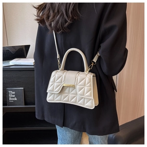 Detalle del bolso acolchado crema con cierre dorado y asa de mano de cuero