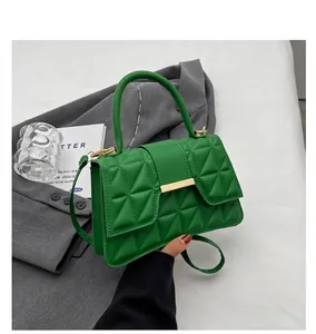 Detalle del bolso mini acolchado verde con costuras triangulares y cierre de metal dorado