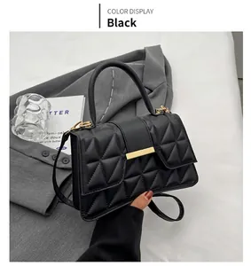 Detalle del bolso bandolera negro acolchado con hebilla dorada sobre un traje