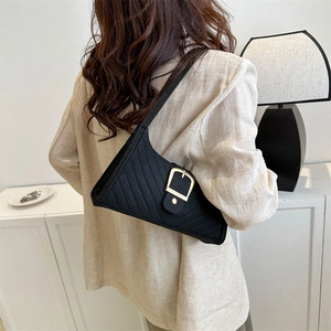 Minimalist black quilted underarm bag with asymmetric triangular silhouette and gold buckle