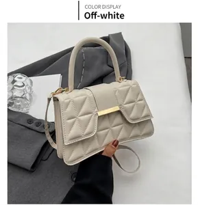 Detalle de bolso acolchado blanco crema con cierre de metal dorado y asa suave