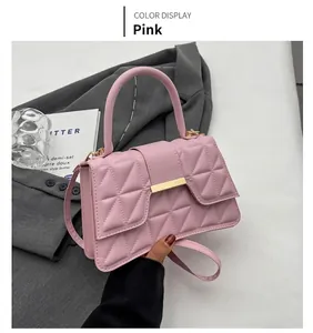 Detalle de bolso cuadrado pequeño rosa con acolchado geométrico y hebilla de metal dorado