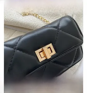 Macro detail of golden metal turn-lock closure on black quilted leather handbag