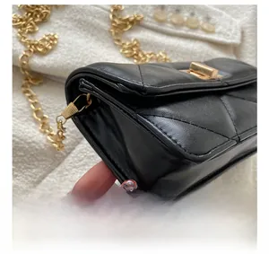 Close-up of black quilted leather texture and gold metal chain strap on a flap bag