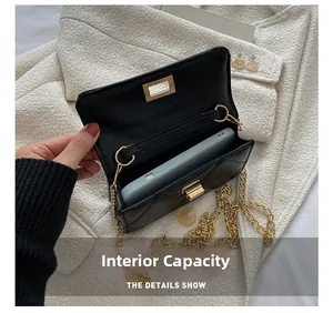 Detail showing the internal capacity of the black quilted chain bag with a smartphone