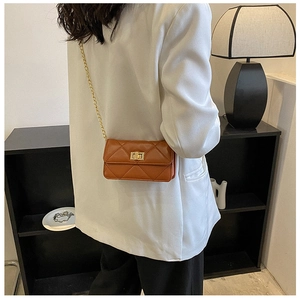 Detail of a brown quilted leather crossbody bag with gold chain strap on a model