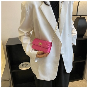 Detail view of fuchsia quilted mini bag with gold lock on white blazer model