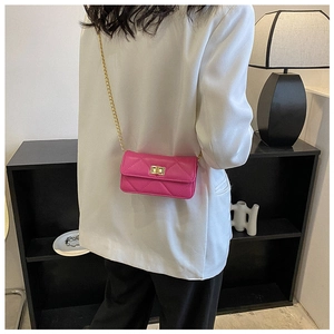 Detail view of mini rose red quilted chain bag shown on a model in a white blazer