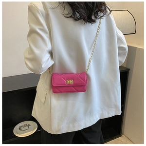 Detail view of pink quilted crossbody bag with gold chain strap on a white suit jacket