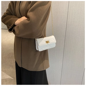 Detail shot of a white quilted crossbody bag with gold chain strap and metal clasp