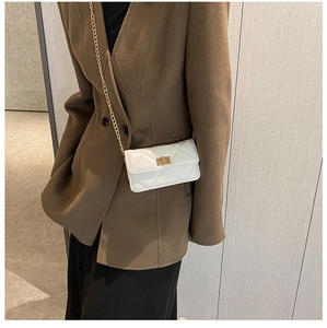 White quilted square bag with gold chain strap and turn-lock shown on shoulder