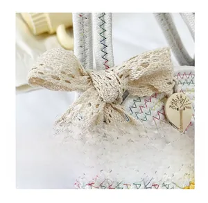 Détail d'un sac de plage tissé avec nœud en dentelle, coutures colorées et bouton bois