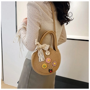 Détail du sac rond en paille avec fleurs colorées et nœud en dentelle blanche élégant
