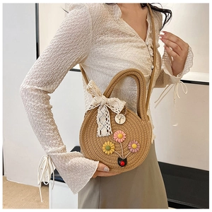 Détail du sac en paille tressé à la main avec fleurs et nœud en dentelle sur mannequin