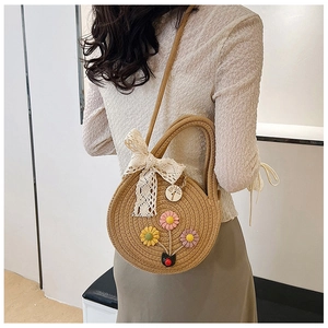 Dettaglio borsa in paglia intrecciata con fiori 3D in maglia e fiocco in pizzo chic