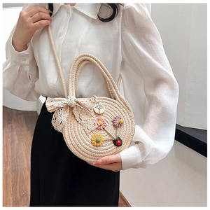 Détail du sac rond en paille tissé à la main avec fleurs et décoration de nœud en dentelle