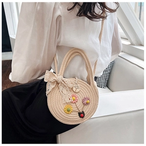 Vista dettagliata di una borsa in paglia intrecciata rotonda con accenti floreali