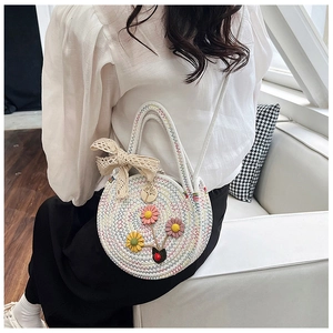Détail du sac à bandoulière rond tressé avec fleurs 3D et nœuds en dentelle délicats