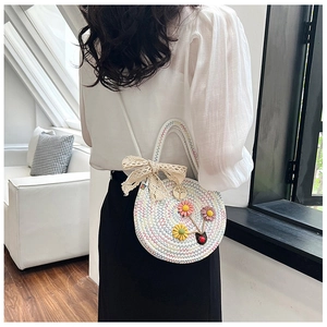 Détail d'un sac rond tissé blanc avec fleurs colorées et nœud en dentelle