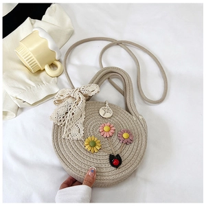 Dettaglio ravvicinato di una borsa tonda intrecciata con decorazioni floreali 3D e pizzo