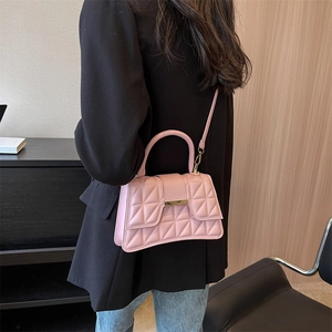 Bolso bandolera acolchado rosa con cierre dorado mostrado por una modelo elegante