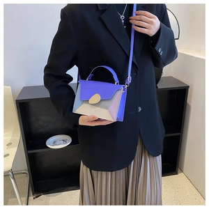 Détail du sac bandoulière bicolore avec fermoir doré en forme de goutte d'eau et sangle