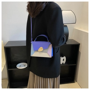 Détail du sac à bandoulière bicolore élégant avec boucle métallique en forme de feuille