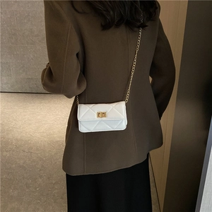 Elegant white quilted mini crossbody bag with gold chain strap worn with brown blazer