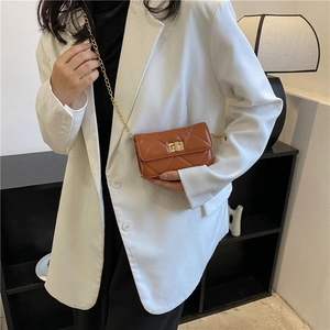 Brown quilted mini square crossbody bag with gold chain strap shown on model in white suit