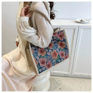 Detail of navy jacquard tote bag featuring vibrant red and orange floral patterns