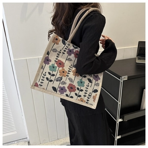 Detail of canvas tote bag featuring colorful floral patterns and woven shoulder strap