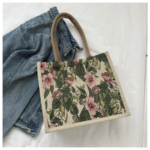 Flat lay of floral jacquard tote bag with blue denim jacket on white fabric background