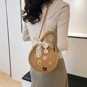 Borsa a tracolla rotonda in paglia intrecciata con fiori ricamati e fiocco in pizzo