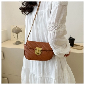 Detail of brown quilted crossbody bag with golden clasp and leather-chain strap
