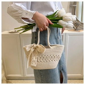 Detail of hand-woven off-white tote bag with a lace bow and textured wave pattern