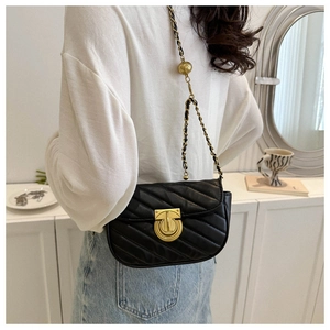 Detail of black quilted crossbody bag featuring a golden ball chain adjuster and metal lock