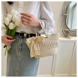 Detail of hand-woven cream tote bag with elegant lace bow on a soft indoor background