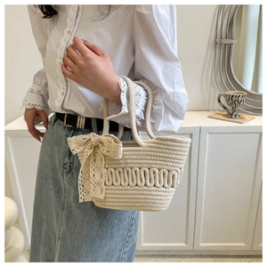Close-up of cream hand-woven tote bag with wave texture and lace bow detail