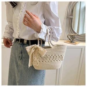 Detail of beige woven tote bag featuring a lace bow and unique wave texture design