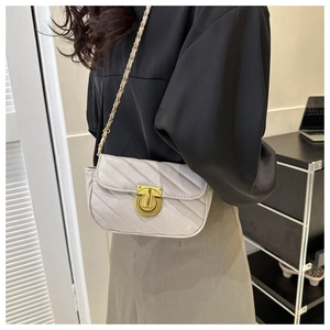 Detailed view of white quilted crossbody bag with gold round lock and leather chain strap