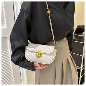 Detail view of white quilted crossbody bag featuring a golden ball chain and round lock