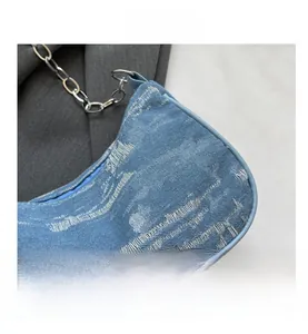 Detail of blue distressed denim shoulder bag with silver chain and leather edges