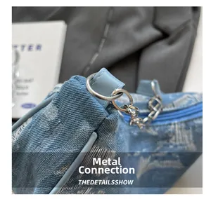 Detail of blue denim bag featuring silver metal rings and chain strap connection