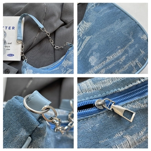 Macro view of distressed denim texture, silver chain strap, and zipper details on a blue bag