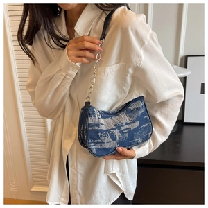 Detailed shot of blue denim armpit bag with frayed fringe and silver chain strap