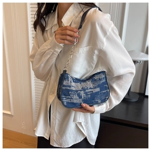 Détail du sac baguette en jean bleu avec franges vintage et bandoulière en chaîne métal