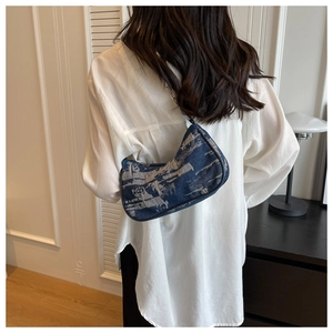 Detail of blue distressed denim half-moon underarm bag with silver chain strap